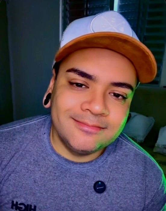 Retrato de Felipe Araujo com boné, sorrindo para a câmera
